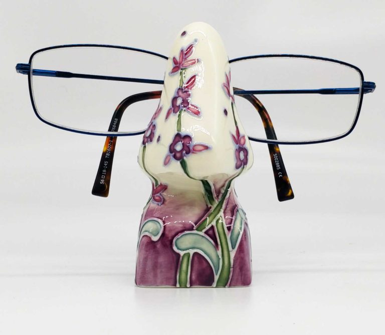Purple floral pattern painted onto this pretty nose shaped eyeglass stand made from earthenware pottery