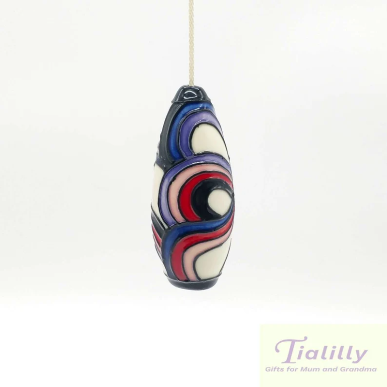 this is an image of a quirky light pull with swirls of red, pink and blue, art decor style for bathroom pull handle
